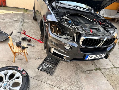 BMW X5 nyitott motorháztetővel, szerszámokkal