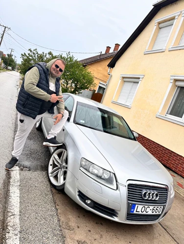 Kolléga pózol az Audi mellett az esős utcán